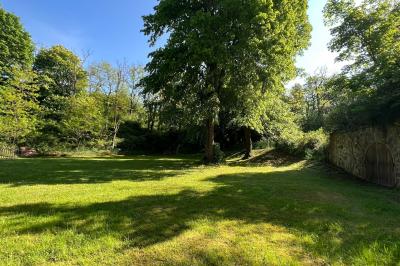 Deux structures en pierre recouvertes de végétation dans un espace herbeux entouré d'arbres.