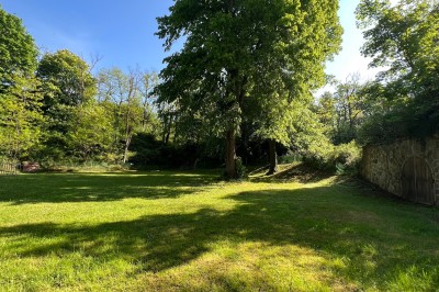 Serveur portant un plateau dans un événement en plein air sous des tentes, avec des invités assis et debout.