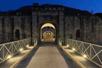 Serveur portant un plateau dans un événement en plein air sous des tentes, avec des invités assis et debout.
