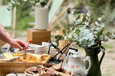 Serveur portant un plateau dans un événement en plein air sous des tentes, avec des invités assis et debout.