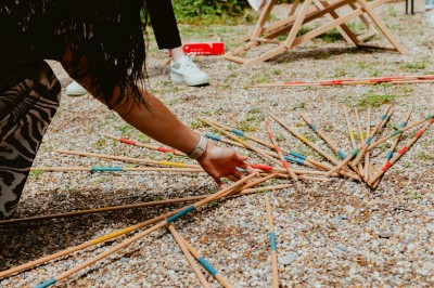 Serveur portant un plateau dans un événement en plein air sous des tentes, avec des invités assis et debout.