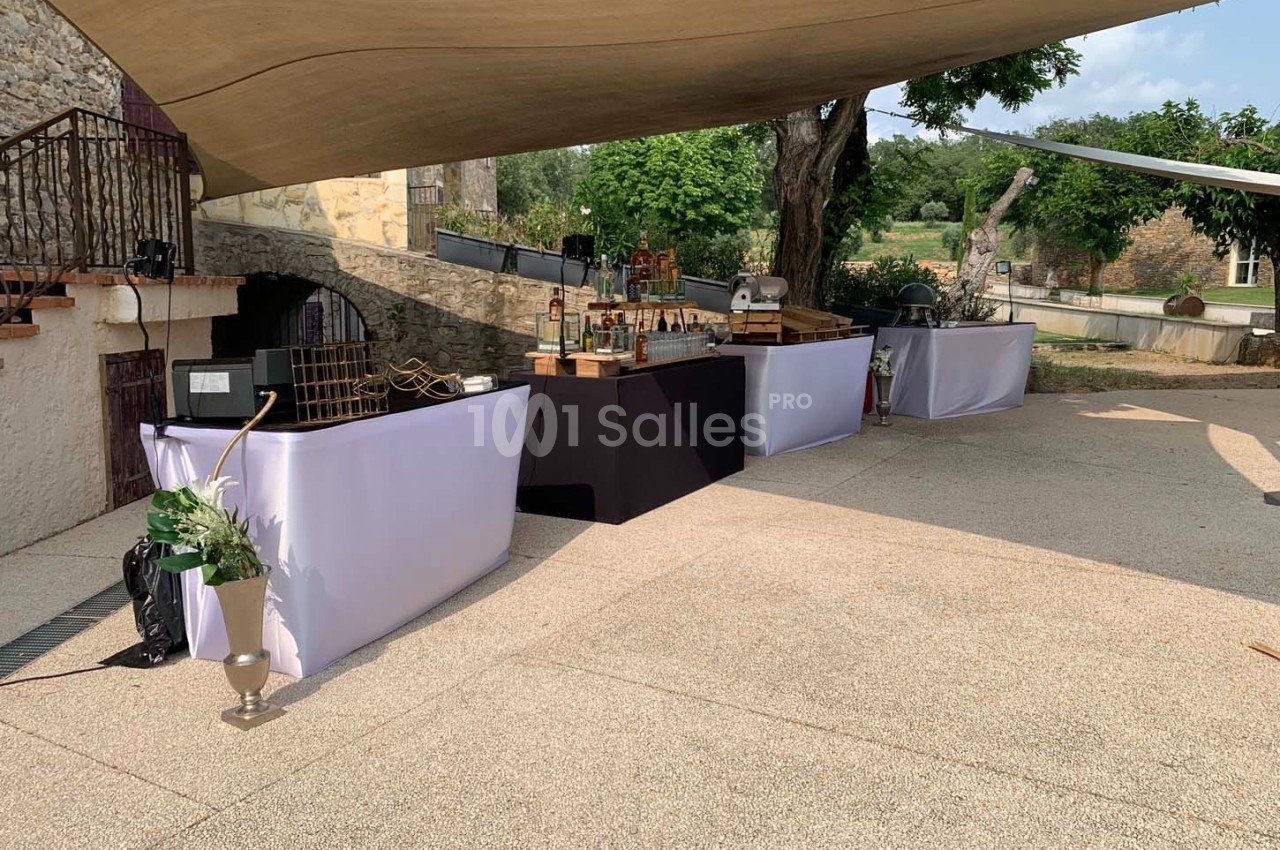 Tables de buffet dressées en extérieur sous une toile tendue, avec un décor champêtre en arrière-plan.