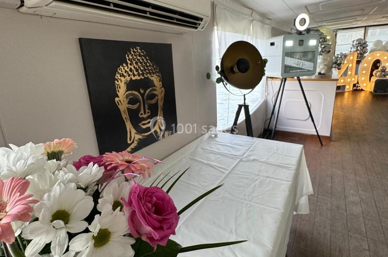 Salle décorée avec des fleurs, une toile représentant un Bouddha, un appareil photo vintage et un chiffre lumineux ’40’.
