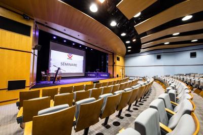 Entrée lumineuse avec tapis foncé, murs blancs, escalier en bois et plantes visibles à travers une cloison vitrée.