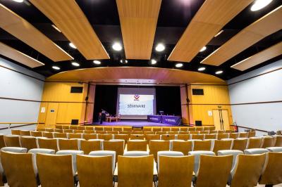 Entrée lumineuse avec tapis foncé, murs blancs, escalier en bois et plantes visibles à travers une cloison vitrée.