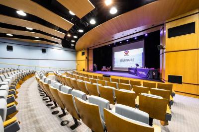 Entrée lumineuse avec tapis foncé, murs blancs, escalier en bois et plantes visibles à travers une cloison vitrée.