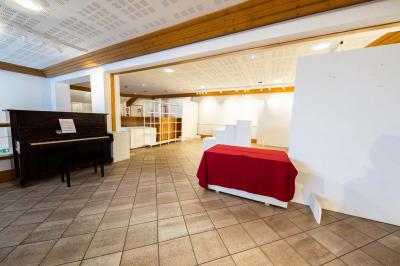 Entrée lumineuse avec tapis foncé, murs blancs, escalier en bois et plantes visibles à travers une cloison vitrée.