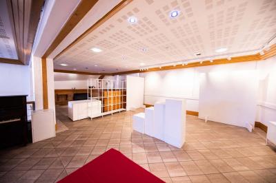 Entrée lumineuse avec tapis foncé, murs blancs, escalier en bois et plantes visibles à travers une cloison vitrée.