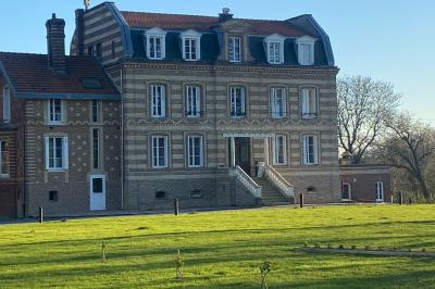 Des chèvres se tiennent près d'une clôture dans un champ herbeux entouré de barrières en bois.