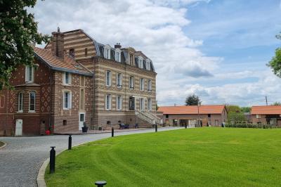 Des chèvres se tiennent près d'une clôture dans un champ herbeux entouré de barrières en bois.