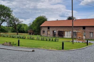 Des chèvres se tiennent près d'une clôture dans un champ herbeux entouré de barrières en bois.