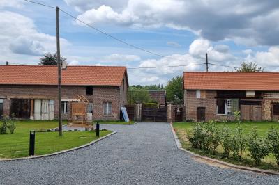 Des chèvres se tiennent près d'une clôture dans un champ herbeux entouré de barrières en bois.