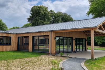 Des chèvres se tiennent près d'une clôture dans un champ herbeux entouré de barrières en bois.