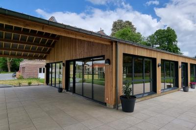 Des chèvres se tiennent près d'une clôture dans un champ herbeux entouré de barrières en bois.