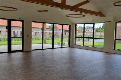 Des chèvres se tiennent près d'une clôture dans un champ herbeux entouré de barrières en bois.