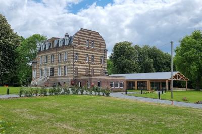 Des chèvres se tiennent près d'une clôture dans un champ herbeux entouré de barrières en bois.