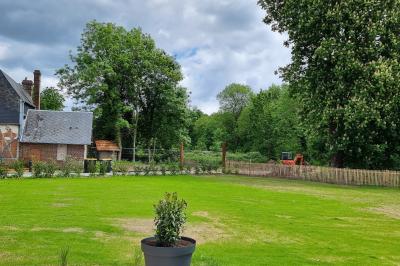 Des chèvres se tiennent près d'une clôture dans un champ herbeux entouré de barrières en bois.