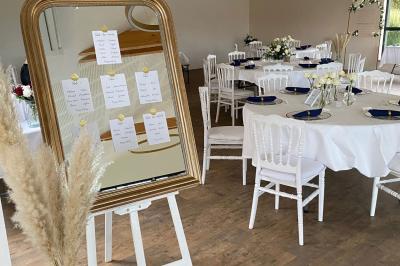 Des chèvres se tiennent près d'une clôture dans un champ herbeux entouré de barrières en bois.