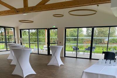 Des chèvres se tiennent près d'une clôture dans un champ herbeux entouré de barrières en bois.