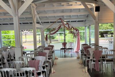 Allée pavée bordée d'arbres et de bâtiments en bois dans un cadre verdoyant sous un ciel dégagé.