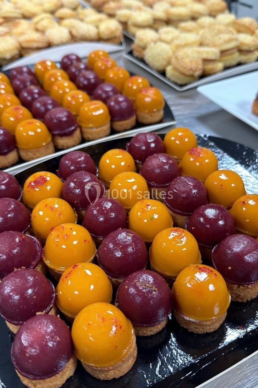 Plateau de petits desserts colorés avec glaçage jaune et rouge, disposés en rangées sur une table.