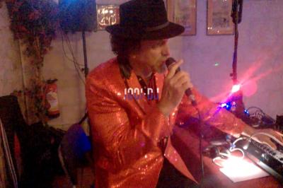 Des artistes en costumes brillants dansent sur une scène illuminée par des projecteurs colorés et un écran lumineux.