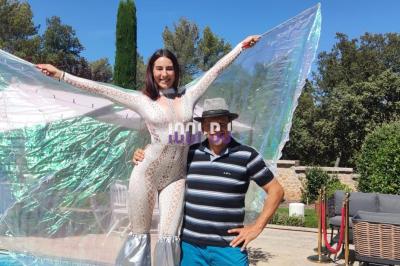 Des artistes en costumes brillants dansent sur une scène illuminée par des projecteurs colorés et un écran lumineux.