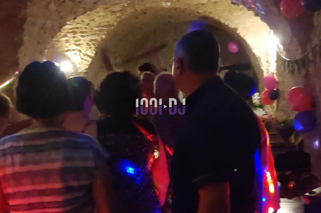 Des personnes dansent dans une cave voûtée éclairée par des lumières colorées et entourée de ballons décoratifs.