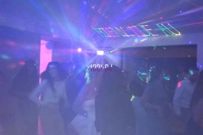 Des artistes en costumes brillants dansent sur une scène illuminée par des projecteurs colorés et un écran lumineux.