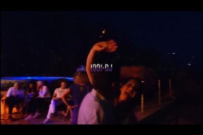 Des artistes en costumes brillants dansent sur une scène illuminée par des projecteurs colorés et un écran lumineux.