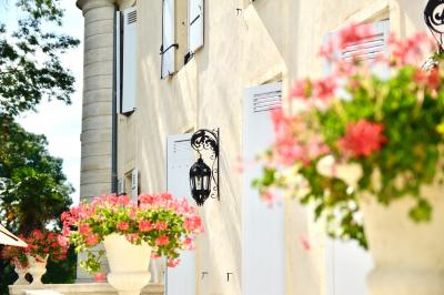Chambre lumineuse avec murs en toile de Jouy rouge, mobilier classique, table basse et fauteuils près d'une fenêtre.