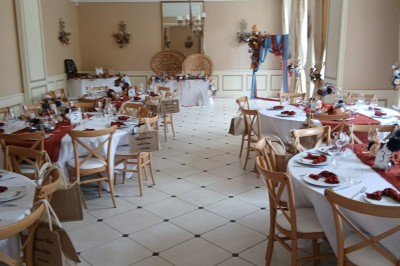 Chambre lumineuse avec murs en toile de Jouy rouge, mobilier classique, table basse et fauteuils près d'une fenêtre.
