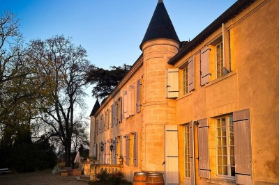 Lampe solaire de jardin en gros plan, éclairant un chemin bordé de feuilles mortes dans un parc au coucher du soleil.