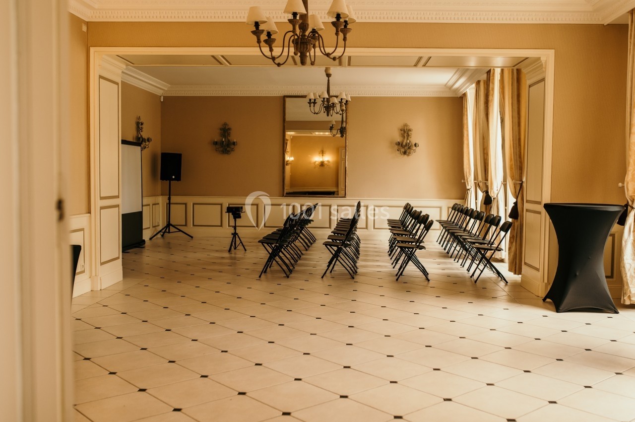 Salle lumineuse avec des chaises alignées, un tableau blanc et un miroir au fond, prête pour une réunion ou un événement.