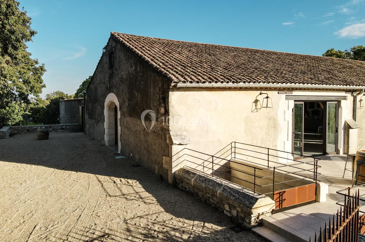 Bâtiment ancien avec murs en pierre, toit en tuiles et entrée moderne accessible par une rampe métallique.