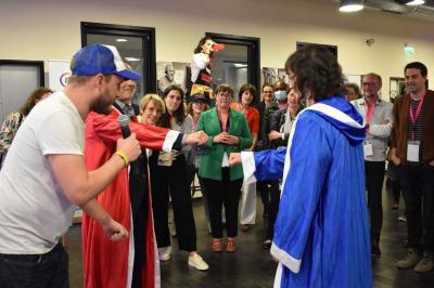 Une personne tient un jeu coloré avec une roue et des compartiments, marqué ’Le Social Bar’.