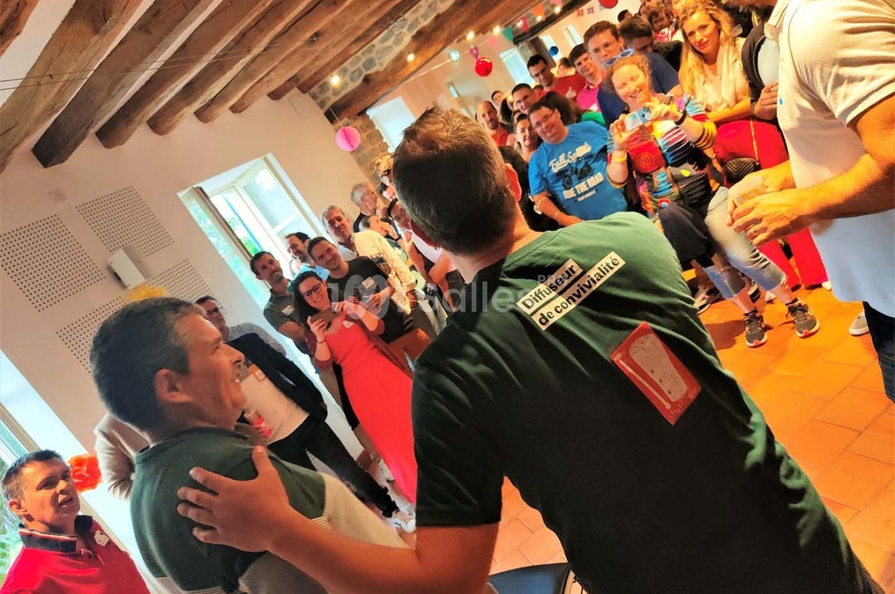 Un groupe de personnes rassemblées dans une salle, certaines souriantes et prenant des photos.