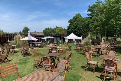 Miniature Location salle Hem (Nord) - O'Green du Château d'Hem #7 Table dressée en extérieur avec nappes blanches, fleurs en centre de table, parasols roses et verdure en arrière-plan.