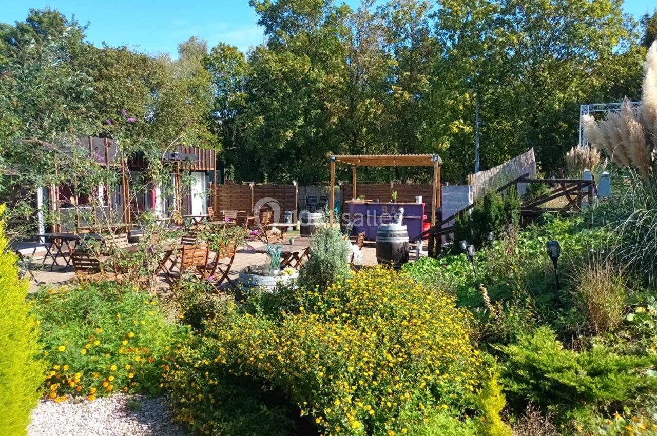 Location salle Hem (Nord) - O'Green du Château d'Hem #27 Jardin aménagé avec des fleurs, des tables en bois, un bar extérieur et des arbres en arrière-plan.