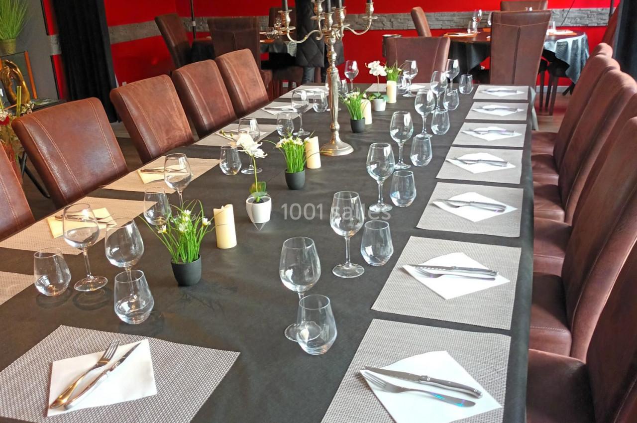 Location salle Hem (Nord) - O'Green du Château d'Hem #29 Grande table rectangulaire dressée avec nappes noires, verres, couverts et serviettes, dans une salle de restaurant rouge.