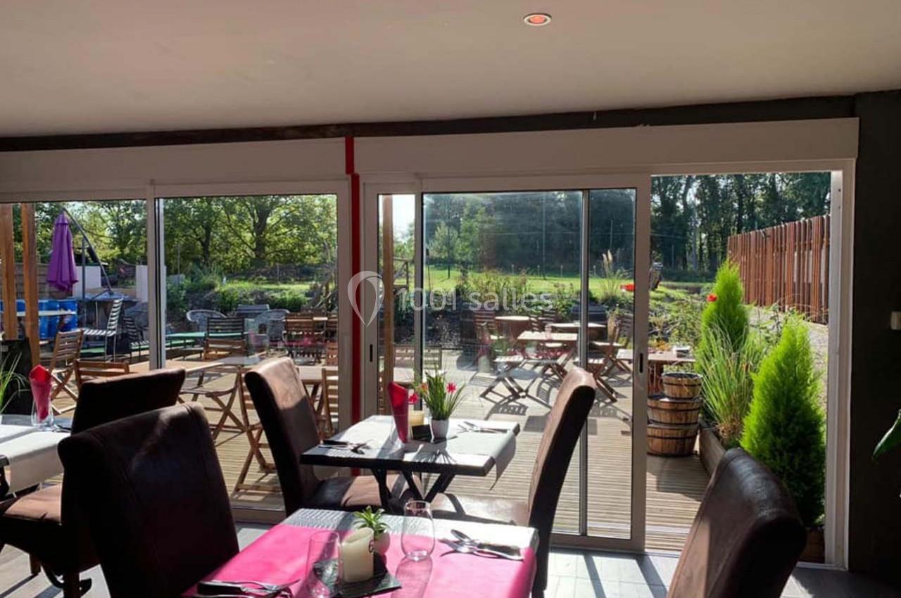 Location salle Hem (Nord) - O'Green du Château d'Hem #11 Salle de restaurant lumineuse avec vue sur une terrasse en bois aménagée et un jardin verdoyant à l'extérieur.