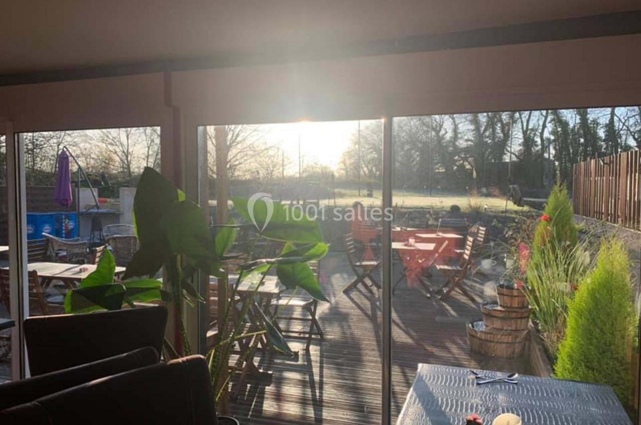 Location salle Hem (Nord) - O'Green du Château d'Hem #2 Salle lumineuse avec vue sur une terrasse en bois aménagée, baignée par la lumière du soleil couchant.