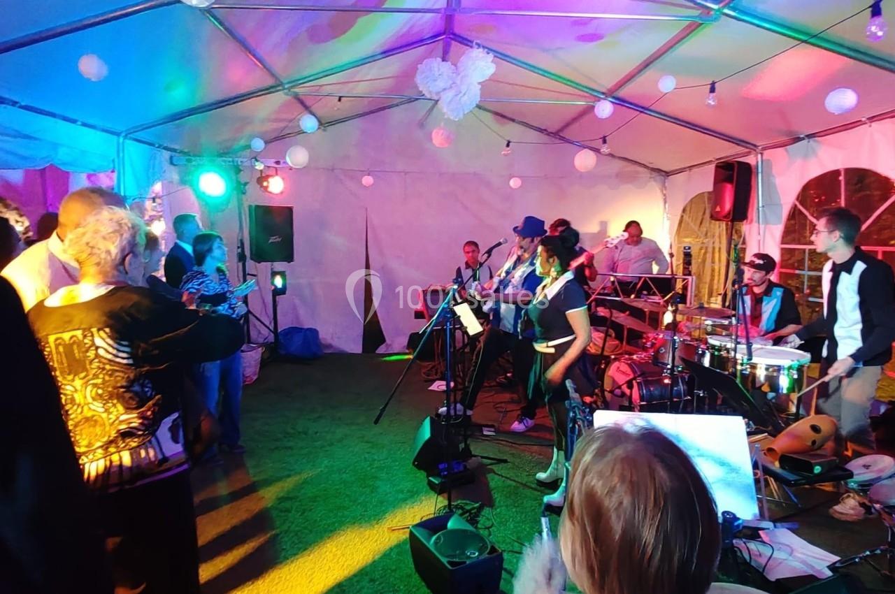 Location salle Hem (Nord) - O'Green du Château d'Hem #3 Groupe de musiciens jouant sous une tente éclairée de lumières colorées, avec un public debout les regardant.