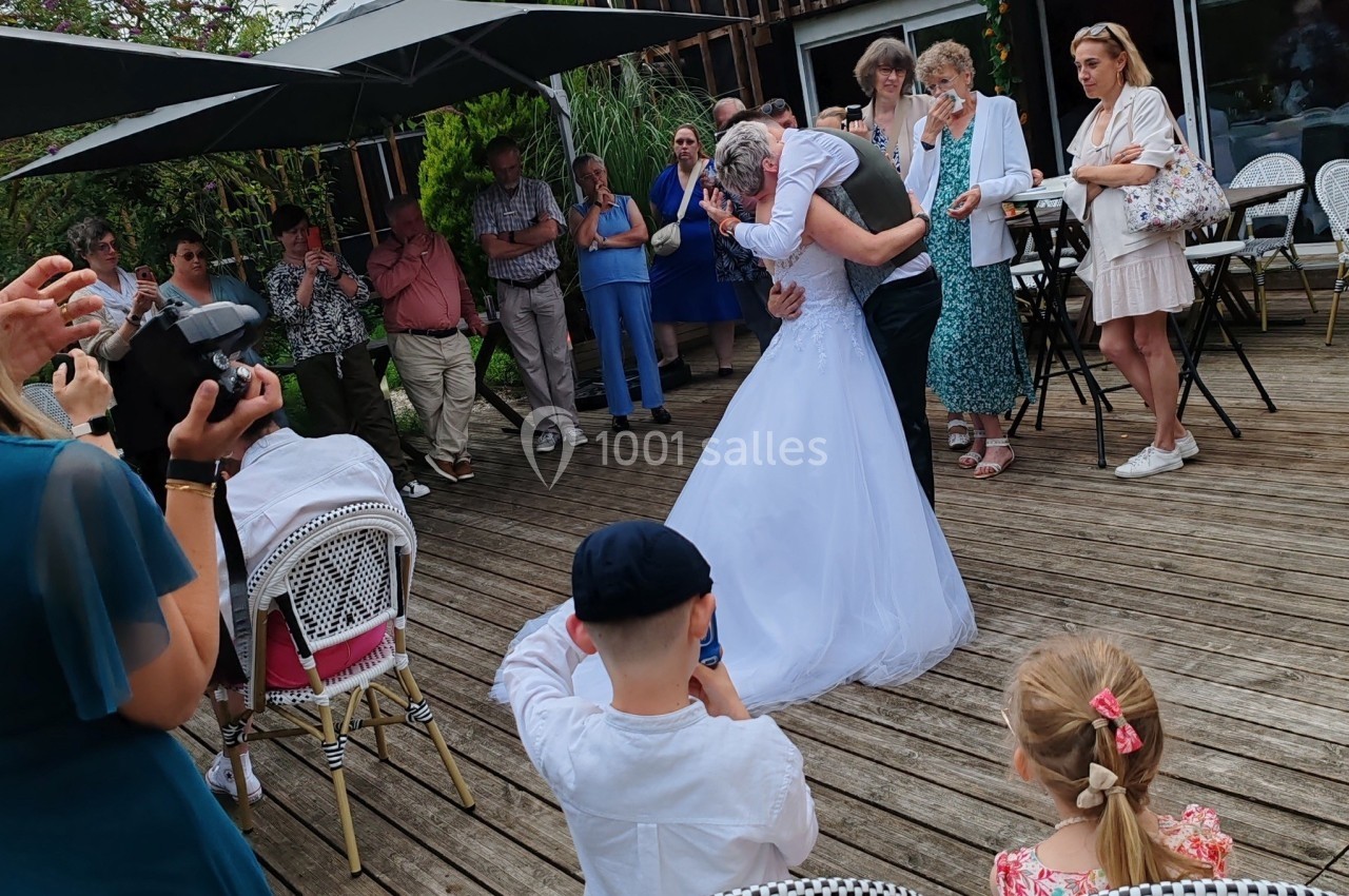 Location salle Hem (Nord) - O'Green du Château d'Hem #8 Un couple de mariés danse sur une terrasse en bois entouré d'invités debout et assis.