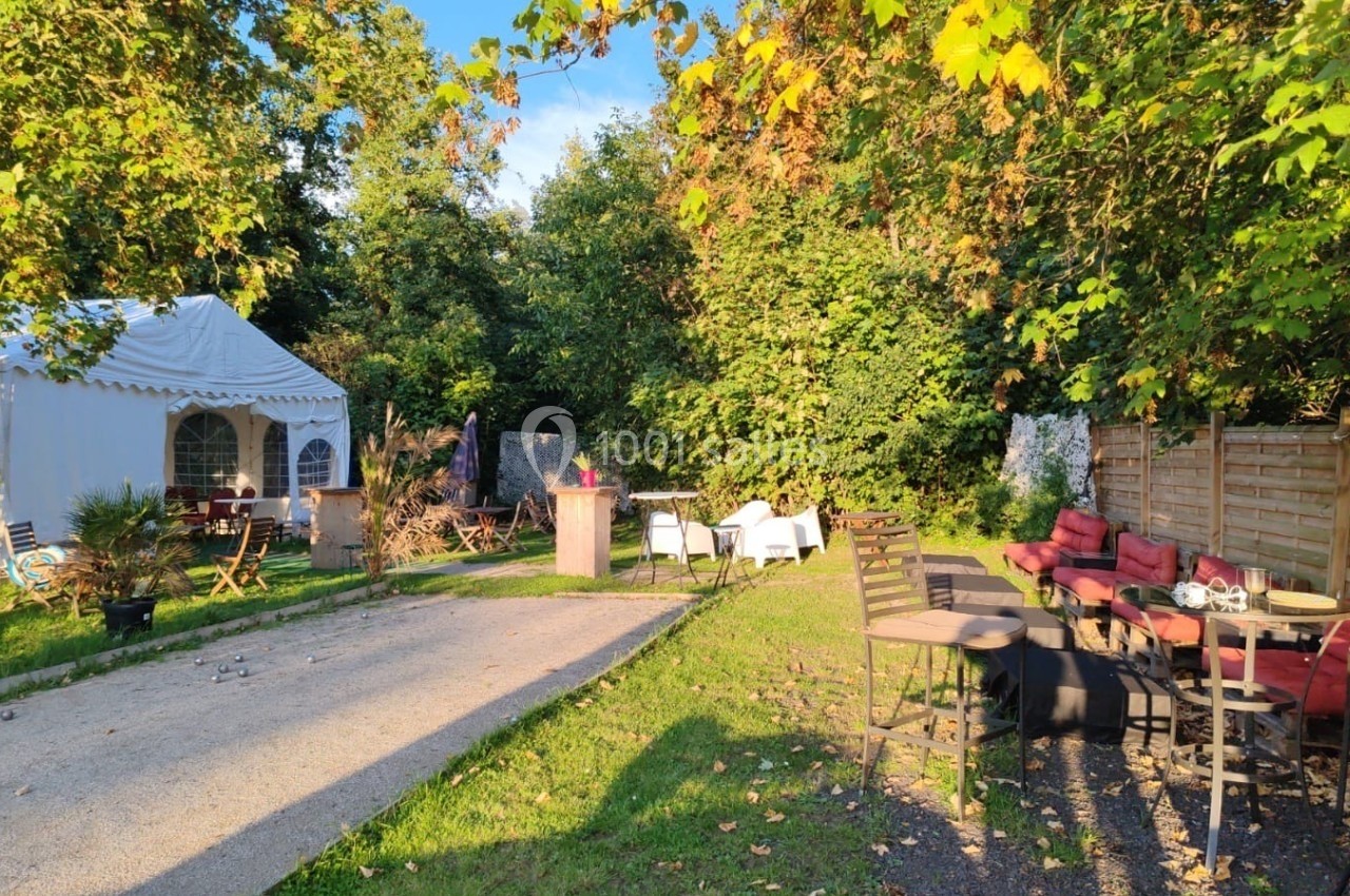 Location salle Hem (Nord) - O'Green du Château d'Hem #18 Espace extérieur avec tables, chaises et une tente blanche, entouré de verdure sous une lumière ensoleillée.