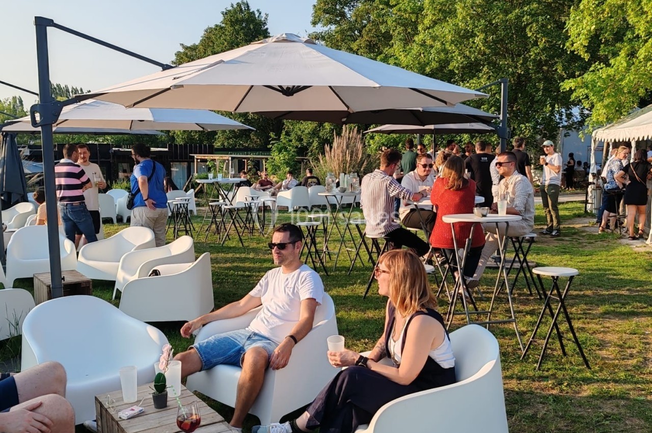Location salle Hem (Nord) - O'Green du Château d'Hem #9 Des personnes discutent et se détendent sur des fauteuils et autour de tables en plein air, sous des parasols, par temps…