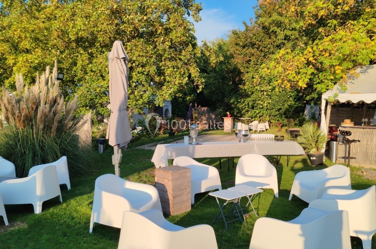 Location salle Hem (Nord) - O'Green du Château d'Hem #3 Mobilier de jardin blanc disposé sur une pelouse, avec une table dressée et un stand en bois sous un auvent.