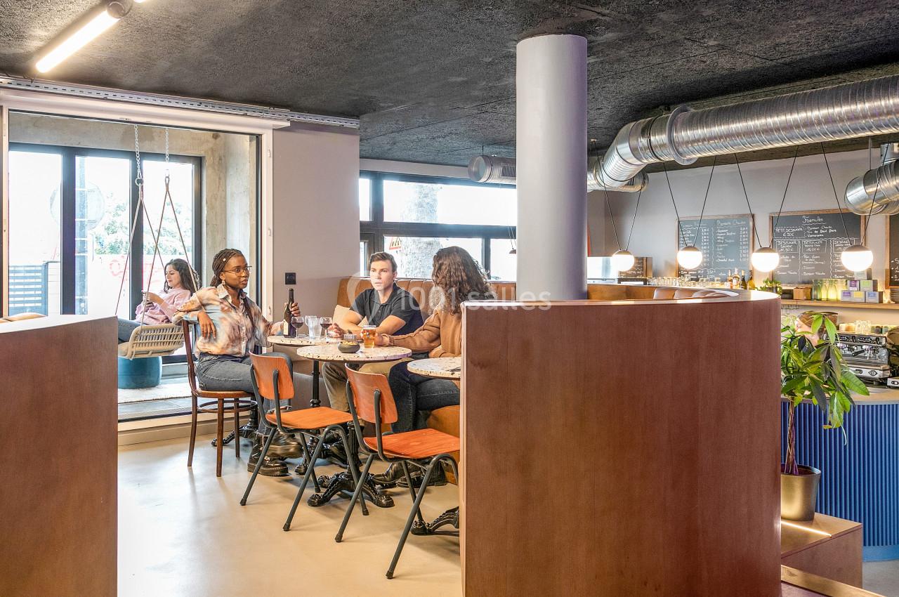 Des personnes discutent autour d'une table dans un café moderne avec un comptoir en arrière-plan.