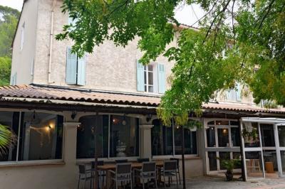 Jardin verdoyant avec pelouse, arbres et buissons, entourant une petite clairière circulaire en béton.