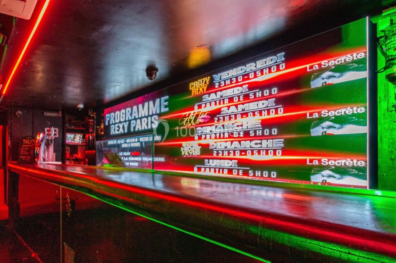 Panneau lumineux affichant le programme d'un club avec éclairage rouge et vert dans un intérieur sombre.